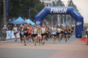 A Side View Of Runners Crossing Finish Line